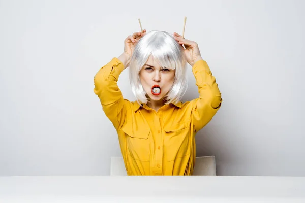 Atractiva mujer en peluca blanca palillos sushi rollos restaurante — Foto de Stock