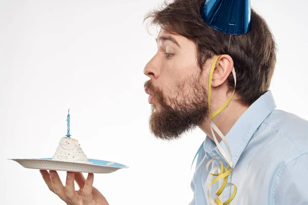 Un homme avec une assiette de gâteau et une chemise bleue sur un fond clair anniversaire fête chapeau d'entreprise — Photo