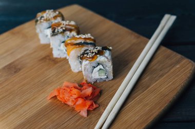 Sushi kırmızı zencefilli çubukları yuvarlıyor tahta tahtaya yakın plan