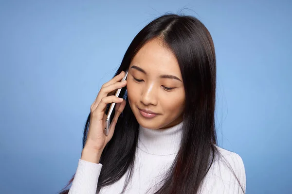 Женщина азиатской внешности говорит по телефону технологии синий фон — стоковое фото