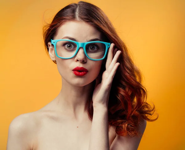 Attractive woman naked shoulders red lips blue glasses studio Royalty Free Stock Photos