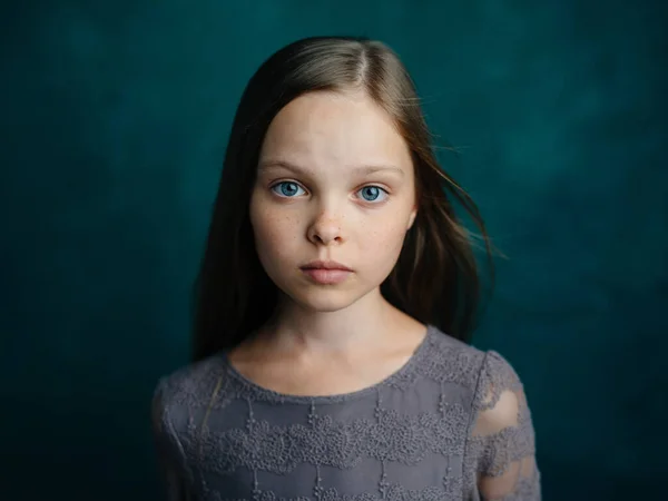 Roztomilý blue-eyed dívka v šedých šatech na zeleném pozadí oříznutý pohled — Stock fotografie