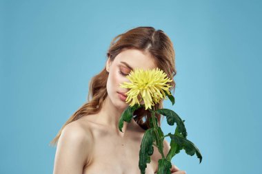 Yüzüne yakın sarı çiçekli güzel bir kadın. Çıplak omuzların kırpık manzaralı portresi.