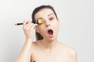 Güzel esmer, çıplak omuzlar yüz bakımına krem sürerken