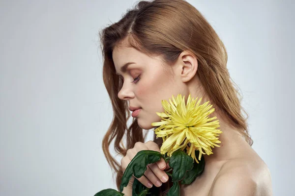 Retrato de uma mulher bonita com uma flor amarela em um fundo claro cortado com Copiar modelo de espaço — Fotografia de Stock