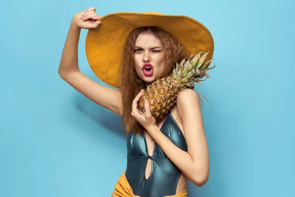 Kvinna i strand hatt ananas innehav baddräkt exotiska frukter blå bakgrund semester — Stockfoto