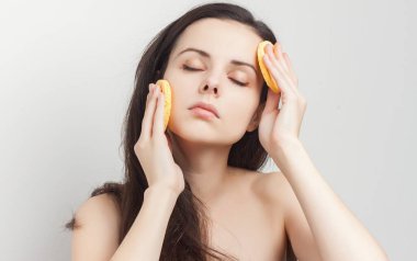 Çıplak omuzlu esmer, elinde süngerle bakıcılık yapıyor.