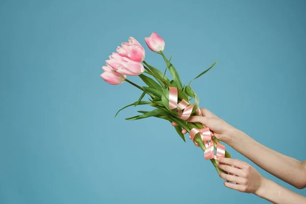 Un ramo de flores en las manos de un regalo de vacaciones romance fondo azul — Foto de Stock