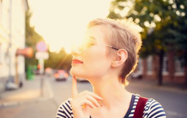 Yazın, kırmızı gözlüklü ve uzun elbiseli romantik bir kadın şehir caddesinde yürüyor.