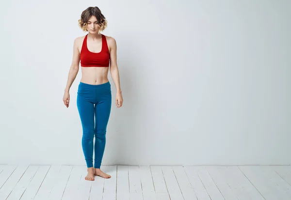 Vrouw in blauw leggings doet sport op een lichte vloer binnen in volle groei — Stockfoto