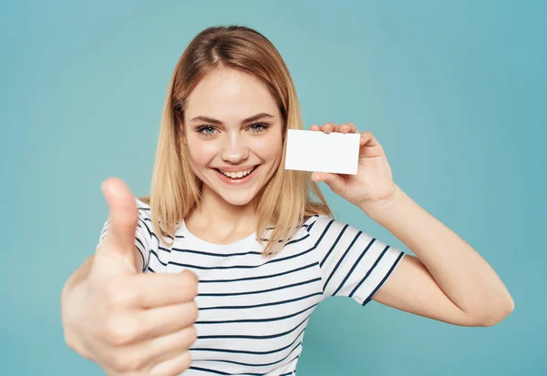 Donna felice su uno sfondo blu gesti con le mani e un biglietto da visita in mano — Foto Stock