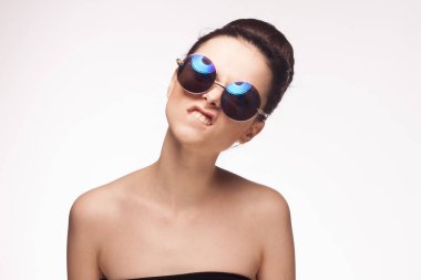 Kadın çıplak omuzlu güneş gözlüklü, parlak arkaplan