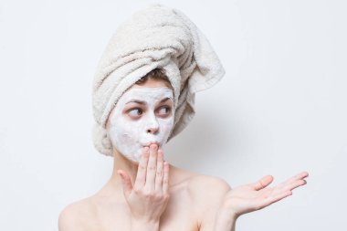 Kafasında havlu ve yüzünde nemlendirici olan bir kadın.