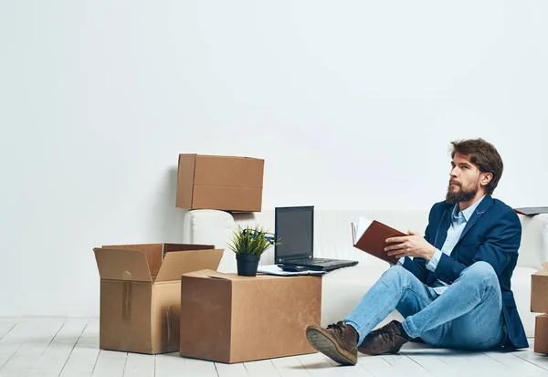 A man sits on the floor of a box with things office moving unpacking official