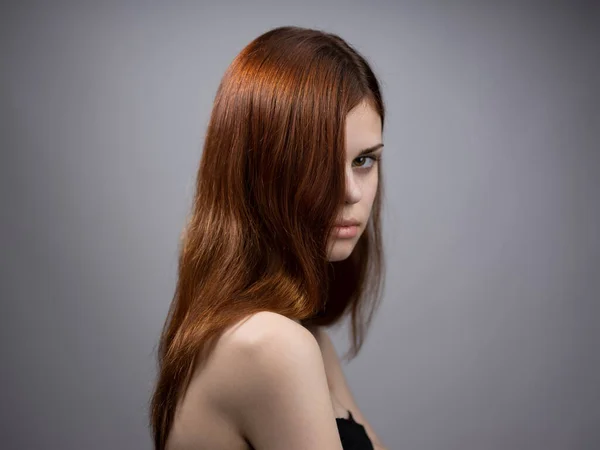 Beautiful woman with loose red hair on a gray background bared shoulders portrait — Stock Photo, Image