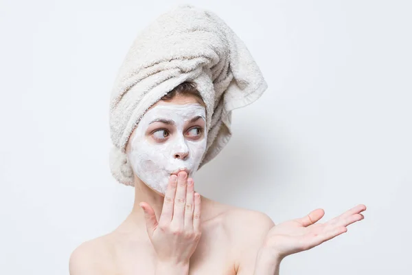 Mulher com uma toalha na cabeça e um hidratante no rosto — Fotografia de Stock
