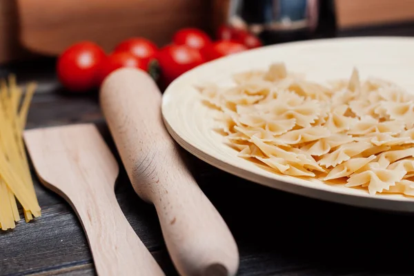 Pasta italiana su un tavolo di legno pomodorini che cucinano — Foto Stock
