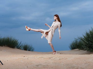 Tişörtlü bir kadın kumsalda geniş adımlarla yürür.