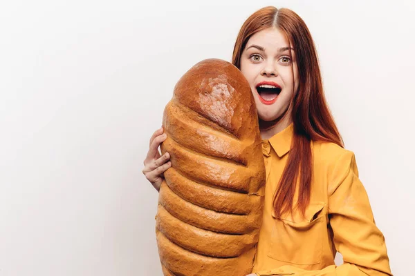 Retrato de una mujer feliz con un pan sobre un fondo claro y un maquillaje de camisa amarilla —  Fotos de Stock