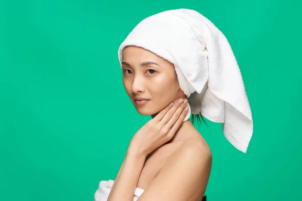 Kvinna asiatisk utseende nakna axlar handduk på huvudet grön bakgrund studio — Stockfoto