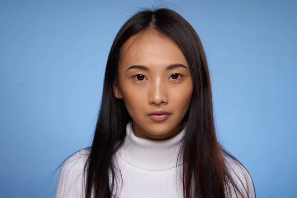 Kvinna asiatisk utseende vit tröja beskärd vy blå bakgrund — Stockfoto