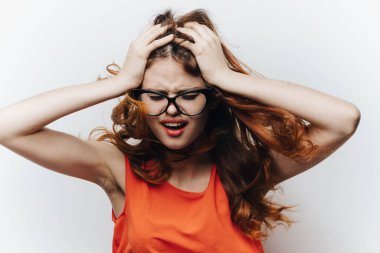 Portakal rengi bir elbise giymiş güzel bir öğrenci. Elinde bir not defteri var. Hafif bir arkaplan üzerinde el hareketi yapıyor.