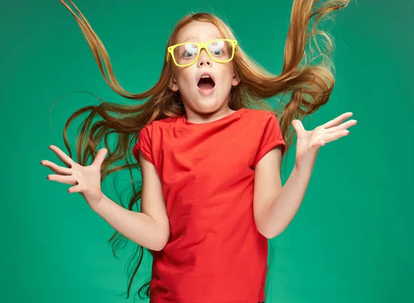 Lány egy piros póló laza haj érzelmek sárga szemüveg Zöld háttér — Stock Fotó