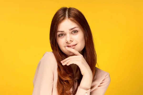 Alegre mulher atraente posando mão perto de rosto amarelo fundo — Fotografia de Stock