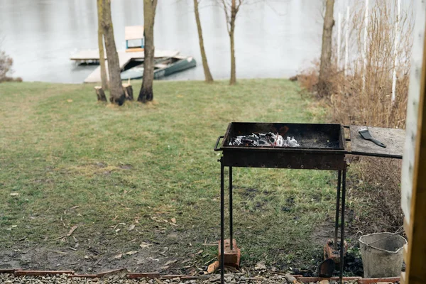 Grill w przyrodzie w pobliżu rzeki i drzew W tle, gotowanie — Zdjęcie stockowe