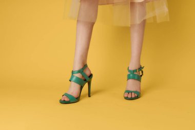 Kadın bacakları yeşil ayakkabılar zarif yaşam tarzı sarı arka plan