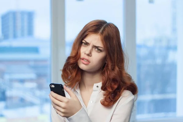 Red-haired woman with a phone in her hands communicating an official — Stock Photo, Image