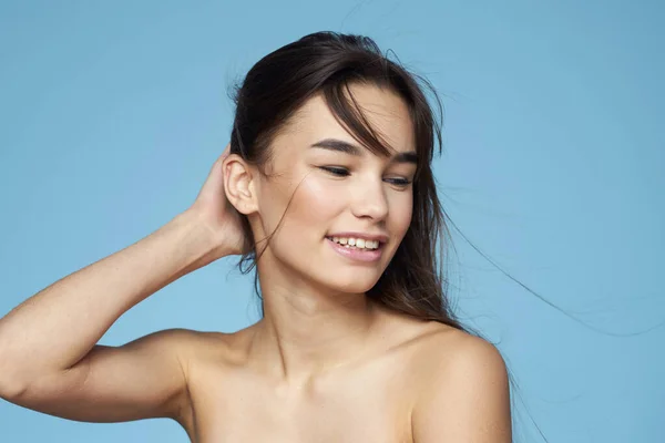 Vrouw met naakte schouders lang haar cosmetica aantrekkelijk blik blauw achtergrond — Stockfoto