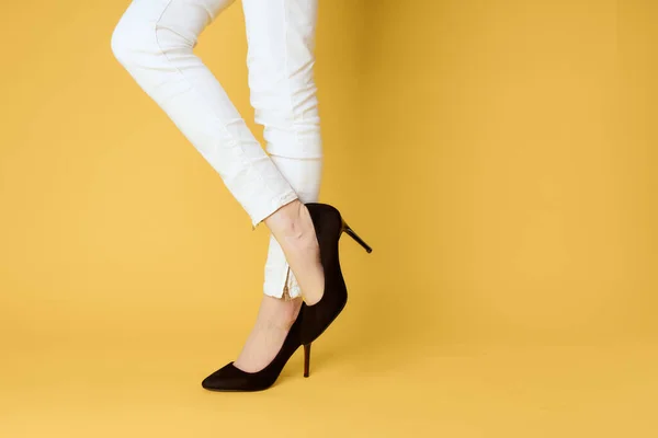 Γυναικεία πόδια μαύρα παπούτσια μόδα ρούχα στούντιο κίτρινο φόντο — Φωτογραφία Αρχείου