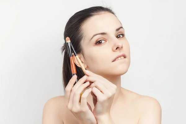 Hübsche Brünette mit einem Pinsel in den Händen beim Auftragen von Make-up-Hautpflege — Stockfoto