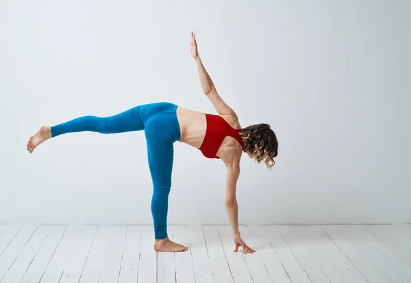 Balans kvinna står på ett ben I ett ljust rum och leggings Yoga asana — Stockfoto