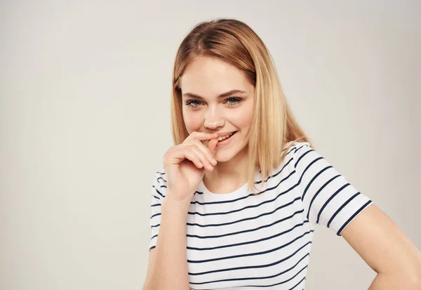 Retrato de uma loira alegre em uma camiseta listrada em um fundo bege vista cortada — Fotografia de Stock