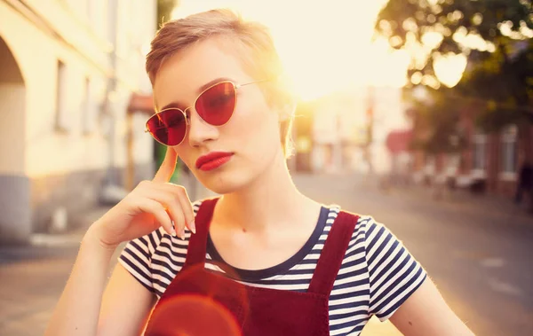 Fashionabla kvinna med kort hår i glasögon och en solklänning promenader ner på gatan på sommaren — Stockfoto