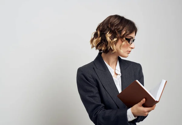 Femme d'affaires dans un costume classique avec un livre dans ses mains sur un fond clair à l'intérieur — Photo