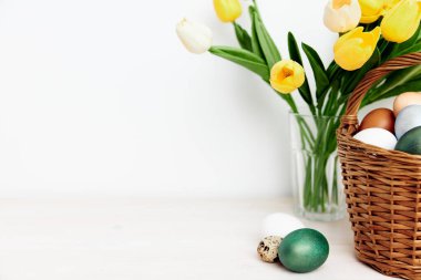 Paskalya yumurtaları ve sarı laleler masada.