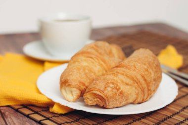 çay tabağında taze kruvasanlar kahvaltı bardağını içeceklerle dolduruyor.