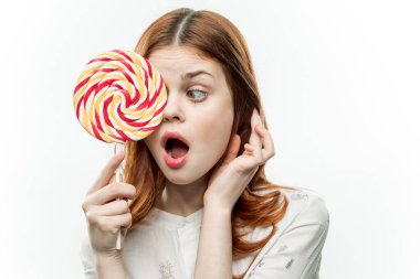 Yüzüne yakın çok renkli lolipopu olan bir kadın tatlıya, duygulara ve açık ağıza baktı.