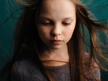 Turkuaz arka planda dağınık saçları olan tatlı küçük bir kız güzel bir yüz.