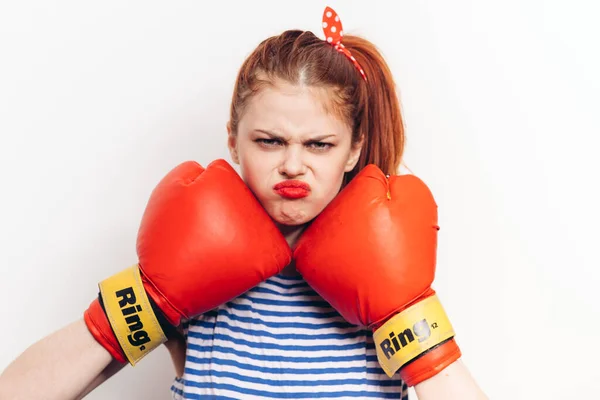 Sportswoman en guantes de boxeo rojos sobre un fondo claro maquillaje brillante rayas camiseta —  Fotos de Stock