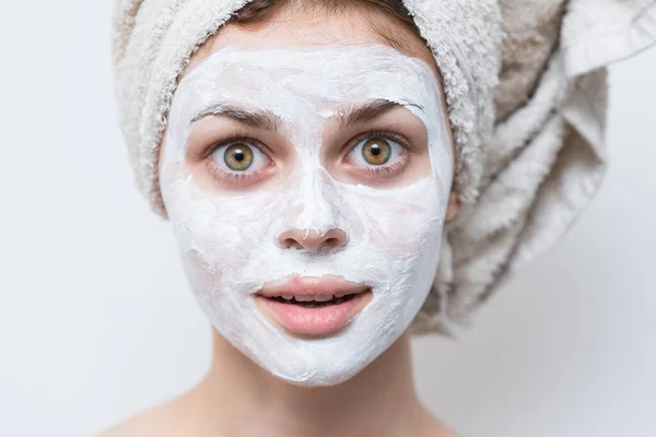 Женщина со сливками на лице полотенце на голове уход за кожей крупным планом — стоковое фото