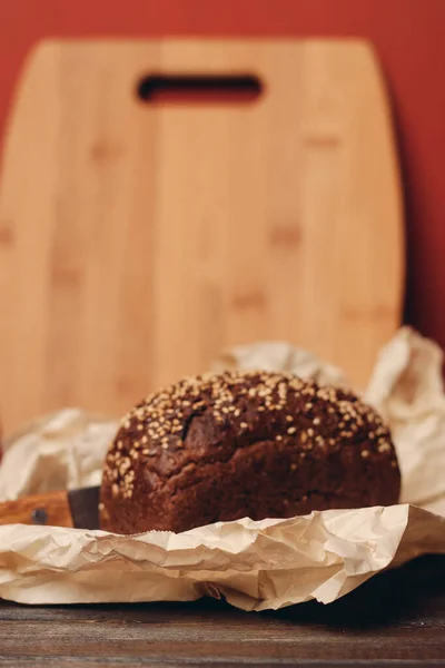 Çavdar ekmeği ahşap bir masa kağıdında keskin bıçak, kırmızı arka plan tahtası. — Stok fotoğraf