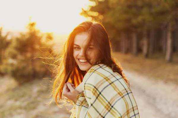 肩に毛布を被った女性は背景の夕日を笑い — ストック写真