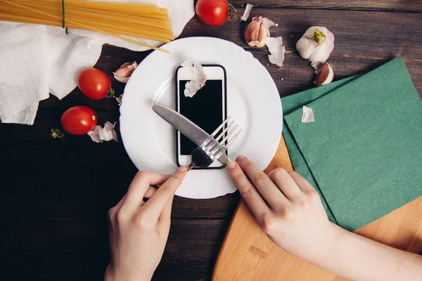 Telefone em uma placa de corte com uma faca comendo mesa de madeira — Fotografia de Stock