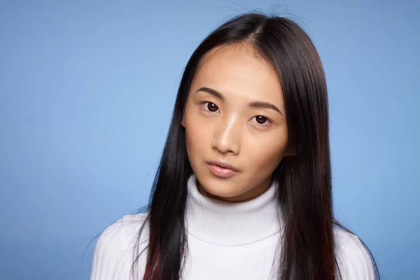 woman asian appearance white sweater cropped view blue background