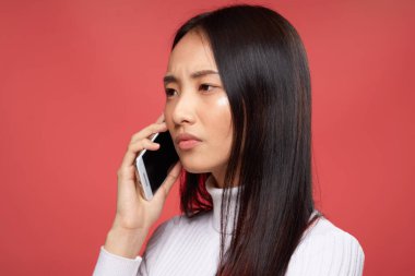 Esmer Asyalı görünümü telefon teknolojisi stüdyo kırmızı arka planda konuşuyor.