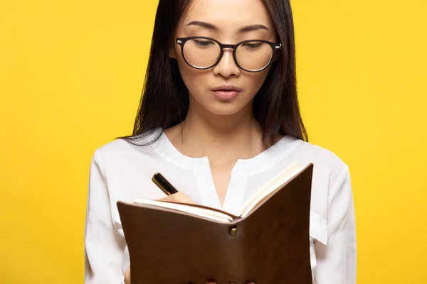 Asiatique femme avec notebook en main apprenant étudiant jaune fond — Photo